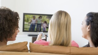 Three women in living room watching television